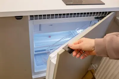 a person is opening an empty refrigerator door at Lukiškės Central Apartment - Self Check-in and Parking Option in Vilnius