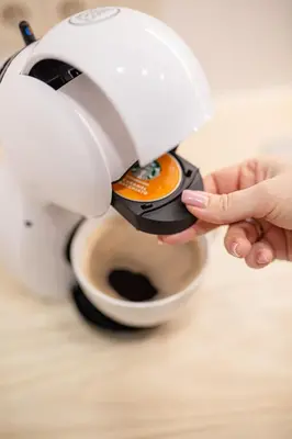a person holding a coffee maker on top of a cup at Lukiškės Central Apartment - Self Check-in and Parking Option in Vilnius