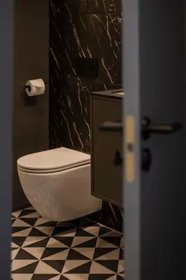a bathroom with a toilet and a black and white tile floor at Kaunas Old Town Art Deco Apartments II in Kaunas