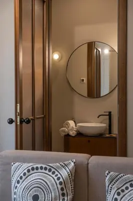 a bathroom with a mirror and a couch with a sink at Kaunas Old Town Art Deco Apartments I in Kaunas
