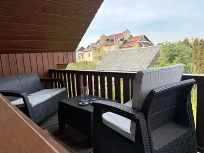a balcony with two chairs and a table and a house at Domus Revado in Birštonas