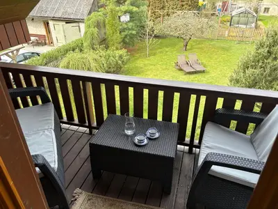 a table and chairs on a balcony with a view of a yard at Domus Revado in Birštonas