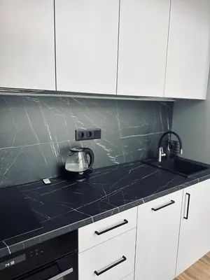 a kitchen with white cabinets and a black counter top at Sunny loft 3 x 24x7 x Close to old town in Vilnius
