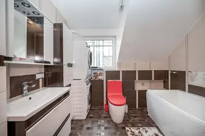 a bathroom with a white tub and a red stool at Cathedral Square Apartment in Vilnius