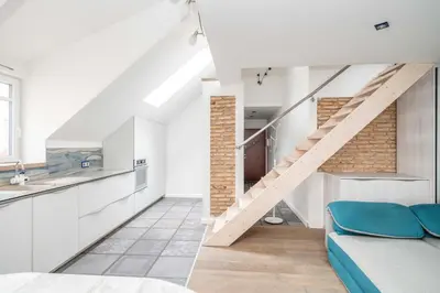 a kitchen and living room with a staircase in a loft at Cathedral Square Apartment in Vilnius