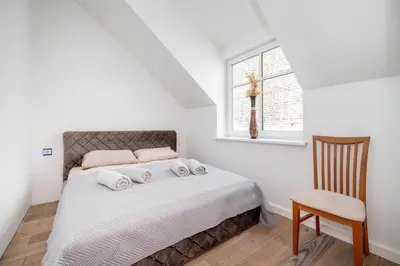 a bedroom with a bed with a chair and a window at Cathedral Square Apartment in Vilnius