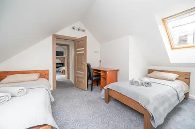 two beds in a room with a desk and a table at Cathedral Square Apartment in Vilnius