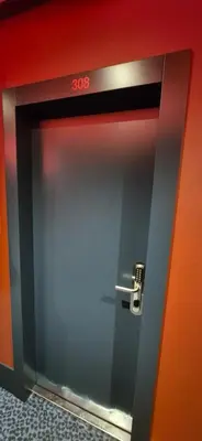 a metal door in a room with a red wall at Private room at Hotel building in Vilnius