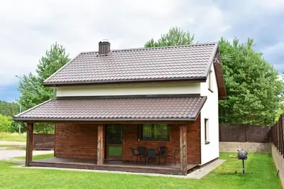 a house with a pitched roof with a deck at Holiday House Strawberry in Druskininkai
