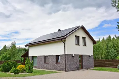 a white house with a black roof at Holiday House Strawberry in Druskininkai