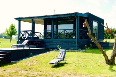 a blue house with two chairs in the grass at DeerHouse in Kaliakiemiai