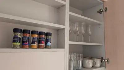 a cupboard with bottles of spices and wine glasses at Kaunas River-View Retreat Free Parking in Kaunas