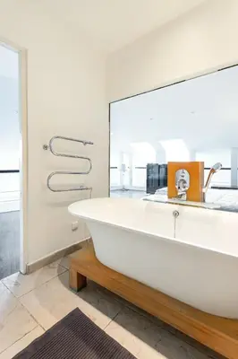 a white tub in a bathroom with a large mirror at Old city gate in Vilnius