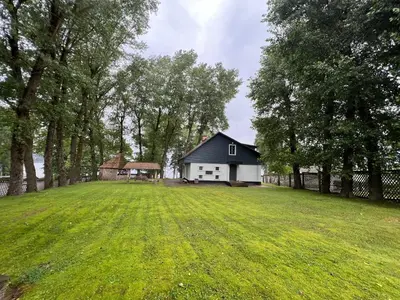 a large yard with a house in the distance at Villa Poilsinė in Balninkai