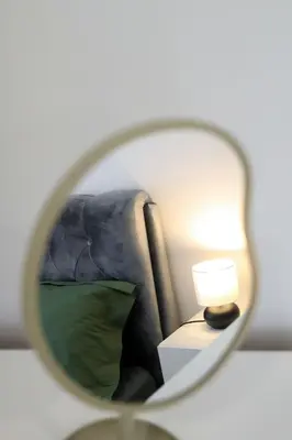 a mirror reflecting a bedroom with a bed and a lamp at Gero laiko oazė in Visaginas