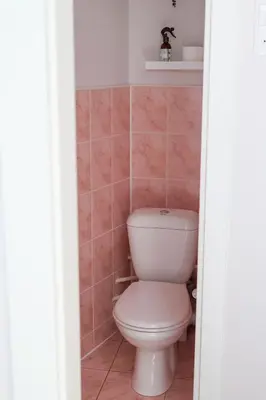 a white toilet in a bathroom with pink tiles at Gero laiko oazė in Visaginas