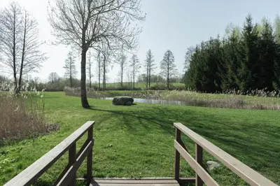 a park with a fence and a tree and a pond at Rubikių Kranto Sodyba in Anykščiai