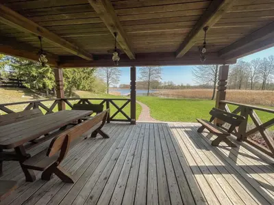 a picnic table and benches on a wooden deck at Rubikių Kranto Sodyba in Anykščiai