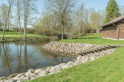 a river with a rock wall next to a building at Rubikių Kranto Sodyba in Anykščiai