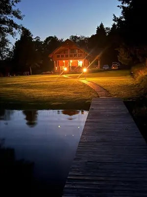 a wooden walkway leading to a house at night at Rubikių Kranto Sodyba in Anykščiai