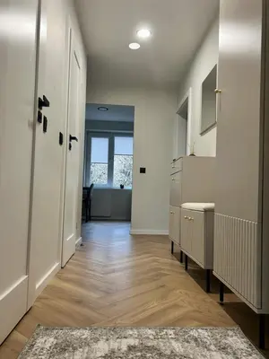 a hallway with white walls and wooden floors and a door at Kolibris in Kaunas