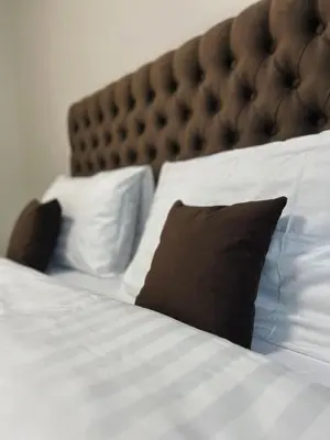 a bed with white sheets and a brown pillow at Kolibris in Kaunas