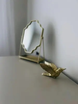 a small bird figurine on a table next to a mirror at Kolibris in Kaunas