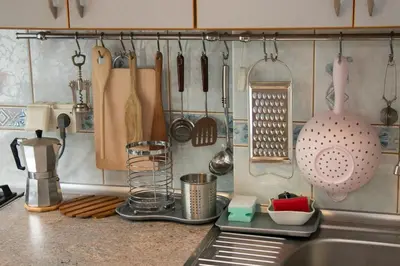 a kitchen counter with utensils hanging from a wall at Comfy Bright Apt in OLD TOWN Your Perfect Location in Vilnius