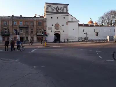 a building on a street with people crossing the street at Comfy Bright Apt in OLD TOWN Your Perfect Location in Vilnius