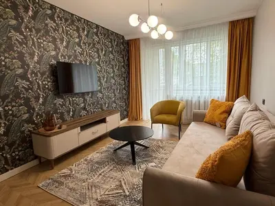 a living room with a couch and a tv on a wall at Naujai įrengti apartamentai Morkus Šiauliai in Šiauliai