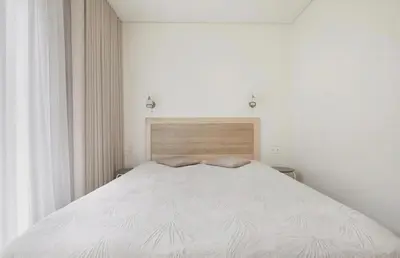 a bedroom with a large white bed with a wooden headboard at Cozy Apartment in Kaunas