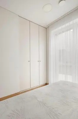 a white bedroom with a bed and a window at Cozy Apartment in Kaunas