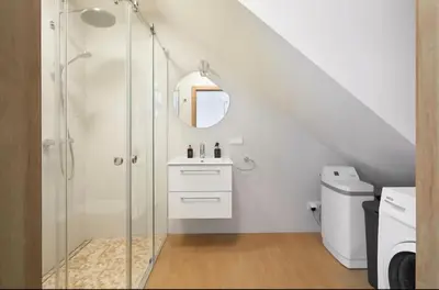 a white bathroom with a shower and a sink at Cozy Apartment in Kaunas