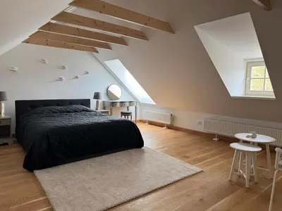 an attic bedroom with a bed and a table at Private Trakai Boutique Historical Authentic Karaim Two Floor Apartment House in Trakai