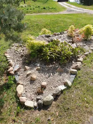 a garden with rocks and plants in the grass at Semeniukų Sodyba in Rakantai