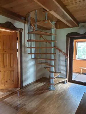 a spiral staircase in a room with a wooden ceiling at Semeniukų Sodyba in Rakantai