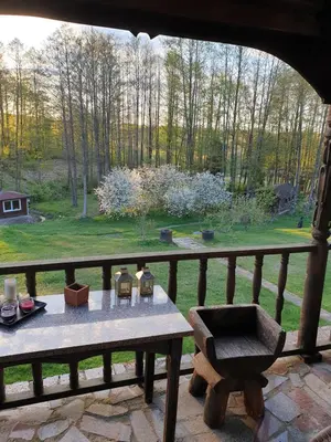a table on a balcony with a view of a garden at Semeniukų Sodyba in Rakantai