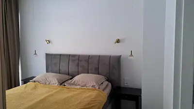 a bedroom with a bed with a headboard and a table at Vilnius Apartment in Vilnius