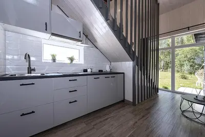 a kitchen with white cabinets and a large window at Namelis Ramybėlė in Siauliškiai