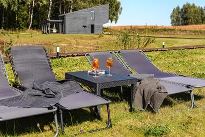 a table and chairs with wine glasses on a field at Namelis Ramybėlė in Siauliškiai