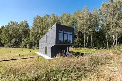 a black and white house in a field at Namelis Ramybėlė in Siauliškiai