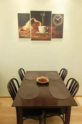 a dining room table with four chairs and a clock at Warmzy Home near Park with Free Parking in Vilnius