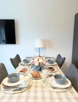 a table with plates and bowls and flowers on it at Miegu - Apartments in Druskininkai