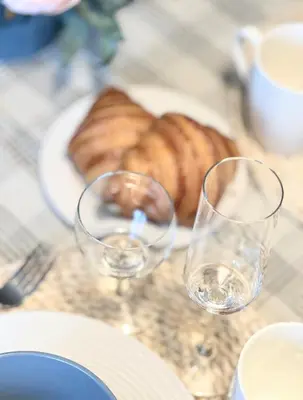 two wine glasses on a table with a plate of bread at Miegu - Apartments in Druskininkai