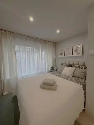 a bedroom with a large white bed with a window at Miegu - Apartments in Druskininkai