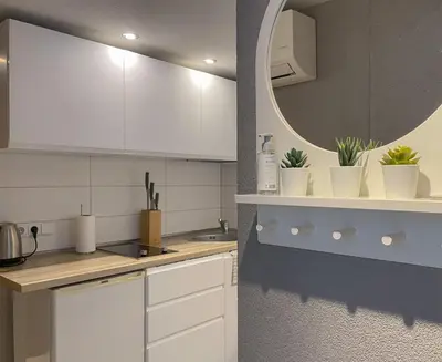 a kitchen with white cabinets and a mirror at Miegu - Apartments in Druskininkai