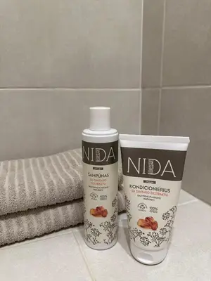 two bottles of nidas on a bathroom counter with towels at Miegu - Apartments in Druskininkai