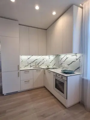 a kitchen with white cabinets and marble counter tops at Apartamentai Varpas in Šiauliai