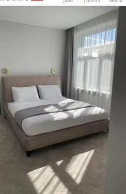 a bed sitting in a bedroom with a window at Apartamentai Varpas in Šiauliai