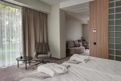 a hotel room with a large bed and a chair at LAJOS Hotel in Birštonas